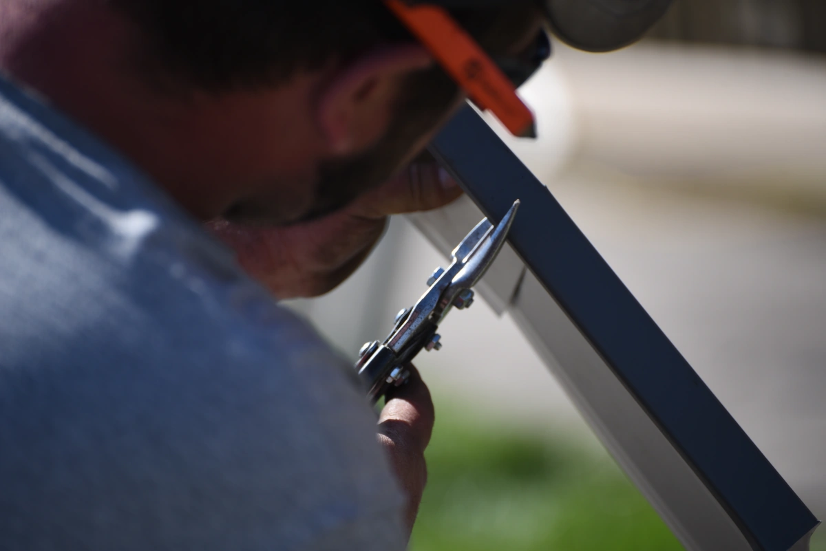 worker using tin snip to cut siding 