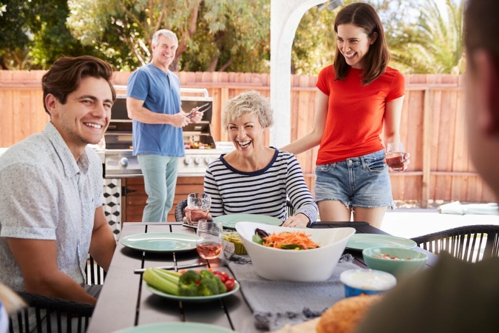 Parents and adult children having a barbecue in the garden