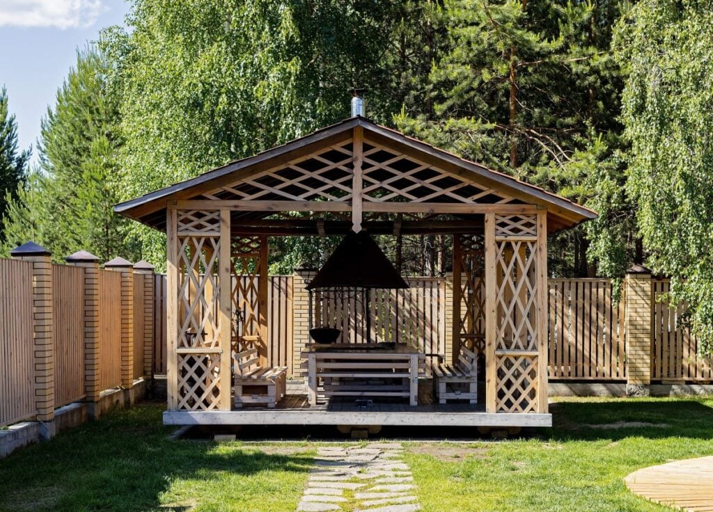 wooden gazebo in backyard with outdoor dining area