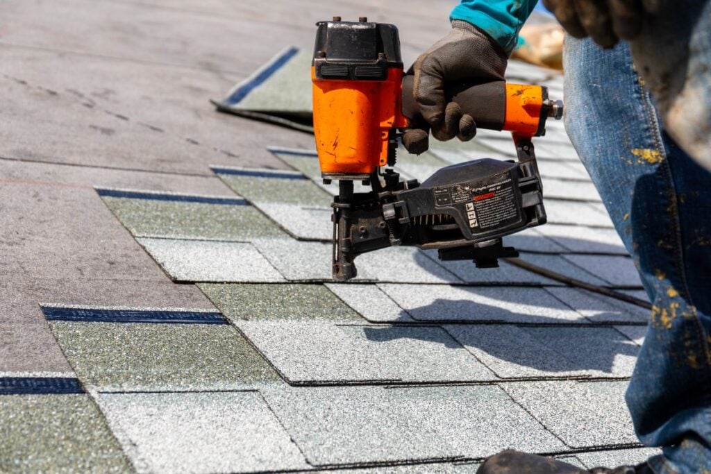 roofer install roof shingles with nail gun